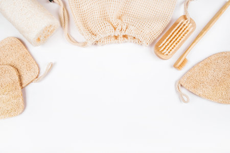 Flatlay with bamboo toothbrush, konjac and loofahs sponges, wooden brush and cotton mesh produce bag isolated on white background. Zero waste concept.の写真素材