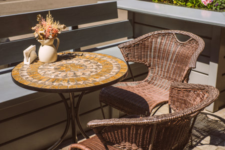 Wicker chairs and round table with flowers on the terrace near the street cafe.の写真素材