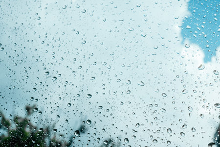 Rain drops on window pane glass surface with cloudy background.の写真素材