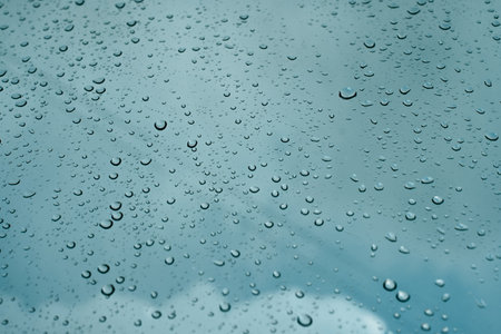 Rain drops on window pane glass surface with cloudy background.の写真素材