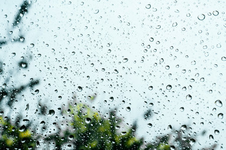 Rain drops on window pane glass surface with cloudy background.の写真素材