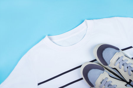 Sport inspired flatlay with white striped t-shirt and blue sneakers isolated on blue background.の写真素材