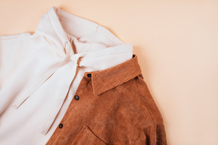 Trendy fall fashion flatlay with hoodie and brown corduroy shirt isolated on beige background.の写真素材