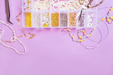 Creative flatlay of different pearl beads with tools for making jewelry, wire string and necklace isolated on pink background.の写真素材