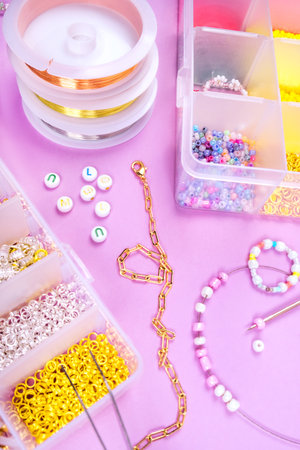Creative flatlay of different pearl beads with tools for making jewelry, wire string and scissors isolated on pink background.の写真素材