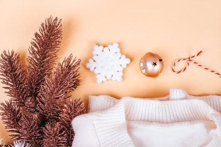 Christmas flatlay with cozy white sweater, rose gold pine tree branches, snowflake, twine string rope and jingle bells isolated on beige background. New Year concept.の写真素材