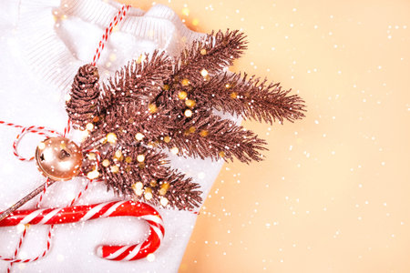 Christmas flatlay with cozy white sweater, rose gold pine tree branches, candy cane, twine string rope and jingle bells isolated on beige background. New Year concept.の写真素材