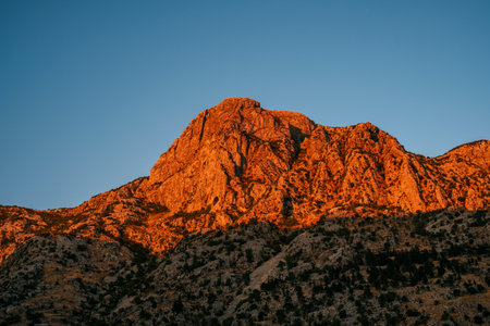 Amazing panorama of mountain peak in the red sunset light with clear blue sky background.の写真素材