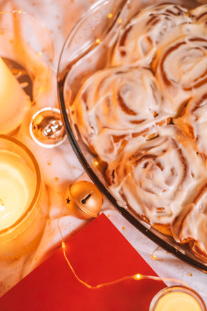Cosy Christmas flatlay with cinnamon rolls, book, candles, lights and jingle bells.の写真素材