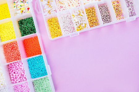 Creative flatlay of different seed and pearl beads in the box on pink background.の写真素材