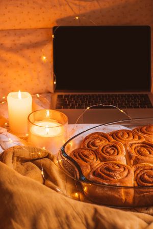 Cosy Christmas flatlay with cinnamon rolls, laptop, candles, lights and jingle bells.の写真素材