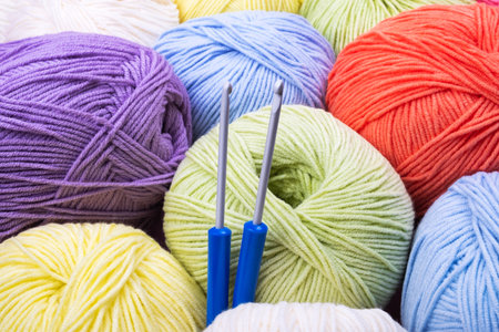 Closeup background of multicolored balls of knitting yarn with two crochet hooks.の写真素材