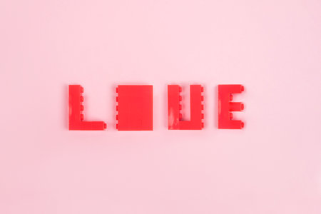 Valentine's Day flatlay with word love made of Lego blocks isolated on pink background.の写真素材