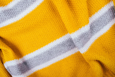 Cozy background of yellow knitted sweater with white and gray stripes.の写真素材