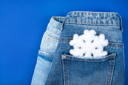 Christmas flatlay with white snowflake in the jeans pocket isolated on blue background.の写真素材