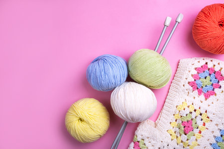 Closeup background of crochet knitting in progress and multicolored yarn balls.