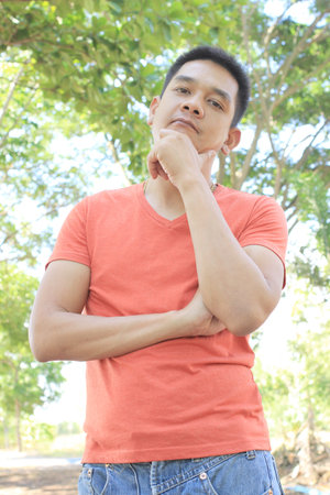 Man is smiling while holding his chin on nature backgroundの写真素材
