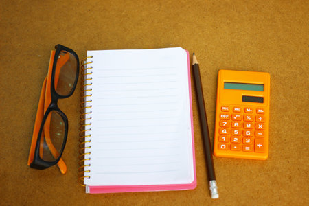 Notebook, eyeglass and calculator on wooden background for financial conceptの写真素材