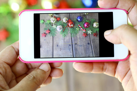 Hand are holding the phone to take photos of Christmas decorationsの写真素材