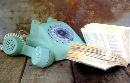 Green vintage telephone and open book on wooden tableの写真素材