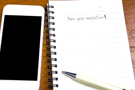 New year resolution with smartphone and pen on wood table