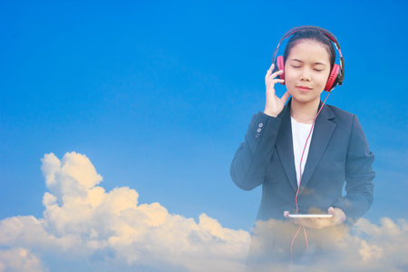 Double exposure beautiful business woman and blue sky. Cute female relaxing by listening music and her face smiling. Concept ideaの写真素材