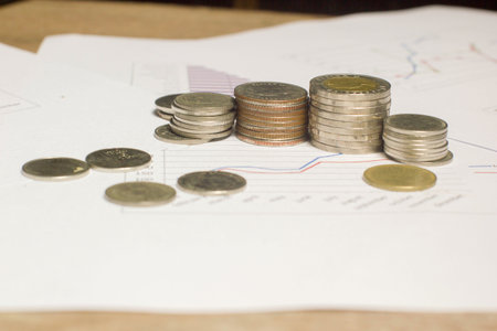 Stack money or coin on white paper graph. Conceptual growing or saving money for business and financeの写真素材