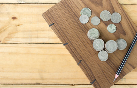 Coins and Pencil on handmade book on wood table with copy space.の写真素材