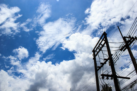 Silhouette electric pole with blue sky and clouds background. Copy space.
