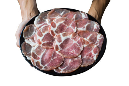 Hand holding pork slice on black plate isolated on white background. Clipping path.の写真素材