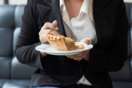 Asian business woman in relax time and eating apple pie in coffee shop. Hand holding  spoon used to eat pie. Apple pie, regional variation apple tart, which the principal filling ingredient is apple.の写真素材