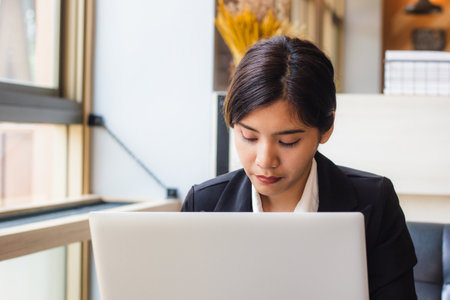 Asian business woman using laptop checking e-mail or message in office or shop. Laptops are essential in today's work. Portable, convenient to use immediately. Business women an important role today.の写真素材