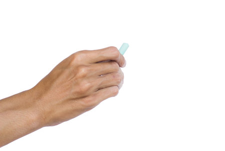 Hand holding green chalk writing something text on empty space. Isolated on white background with clipping path. Chalk is used to write text on a blackboard. Chalk made of plasterの写真素材