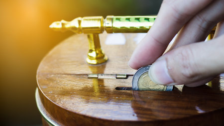 Hand holding coin drops into a wooden piggy bank. Saving coin concept. Conceptual saving money for business or life in future. Concept saving money background for web banner. Investment money Concept.の写真素材