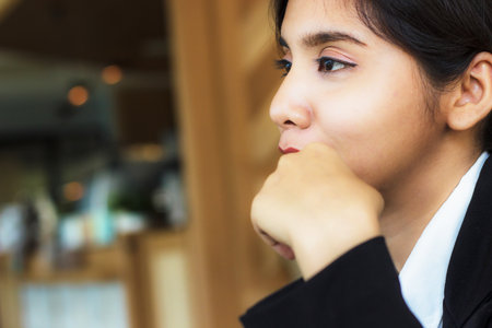 Young business woman is looking to the left and thinking. there is space left. In coffee shop or office. Business women are looking vacant. Boredの写真素材