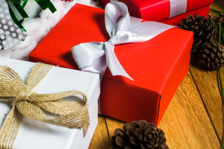 Close up red and white gift on wood table with pine cone background. Christmas background for...