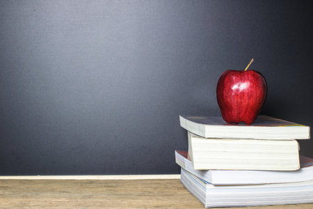 Red apple on book with Blackboard (Chalk Board) as background on wood table. Education concept.