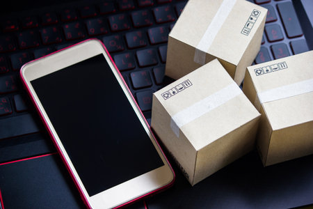 Online shopping concept e-commerce delivery buying service. square cartons shopping on laptop keyboard, showing customer order via the internet and smartphone.の写真素材