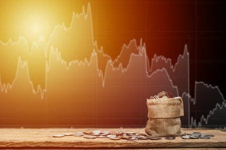 Money bag and money coins on wood table with stock graph as background. Investment conceptual rich with stock for future. Investing stock market concept.の写真素材
