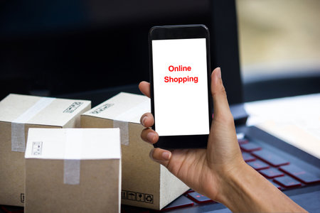 Online shopping concept e-commerce delivery buying service. square cartons shopping on laptop keyboard, showing customer order via the internet on smartphone.の写真素材
