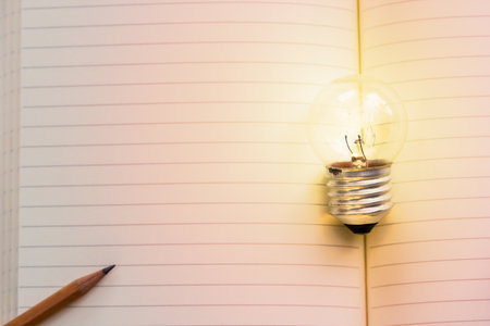 Concept idea. Growing light bulb on vintage book with pencil. Copy space for your text. conceptual...