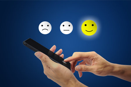 Conceptual the customer responded to the survey. The client using hand choose happy face smile icon on smartphone. Depicts that customer is very satisfied. Service experience and satisfaction concept.の写真素材