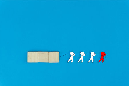Business leadership and teamwork concept. Leadership help his followers to work tirelessly. Red cartoon character help his team drag a wooden on blue background. Differences between leaders and boss.の写真素材