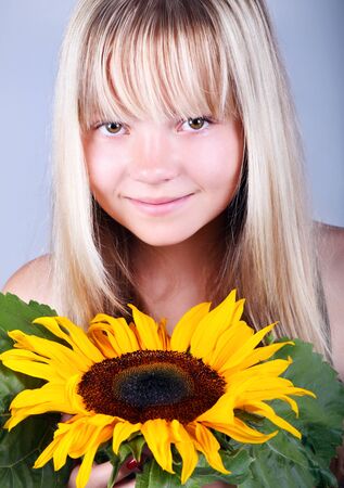 A beautiful happy girl holding a sunflowerの写真素材