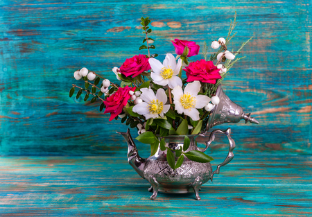 Fresh pink and Christmas roses in metal teapotの写真素材