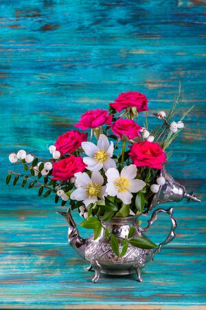 Fresh pink and Christmas roses in metal teapotの写真素材