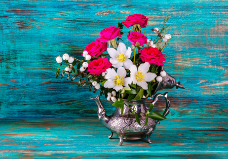 Fresh pink and Christmas roses in metal teapotの写真素材