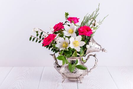 Fresh pink and Christmas roses in metal teapotの写真素材