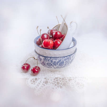 Cherries in an old porcelain cup on the table with crochetの写真素材