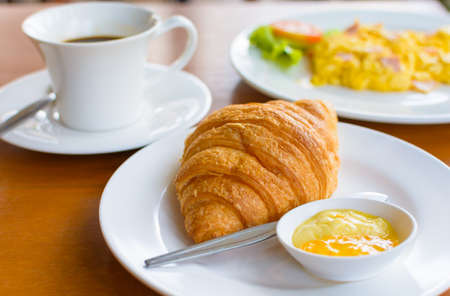 Croissant with coffee and scramble eggs